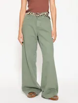 Pantalón de jeans de gabardina teñida en prenda, color verde oliva, de tiro medio-largo. Presenta un calce ancho que se ensancha sutilmente hacia el ruedo.