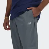 Pantalón jogger deportivo New Balance, color gris oscuro, confeccionado en tejido de poliéster reciclado con tecnología NB DRY. Presenta cintura elástica con cordón de ajuste interno, dos bolsillos laterales y puños elásticos en los tobillos.