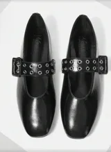 Balerinas negras de charol con punta redondeada, tira sobre el empeine con hebilla metálica y ojalillos.