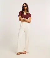 Blusa de manga corta confeccionada en tejido acanalado de algodón con elastano, de color bordó con cuello polo en tono amarillo claro y escote en V.