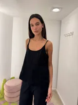 Musculosa negra con breteles finos, confeccionada en tela con bordado inglés y diseño de paneles verticales.