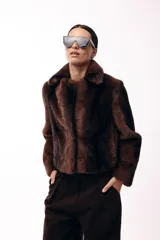 Tapado corto de piel sintética en color marrón chocolate, con cuello solapa amplio y cierre frontal oculto. Presenta una silueta estructurada y elegante.