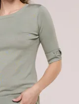 Buzo confeccionado en tejido de punto color beige, de silueta semi entallada, con escote redondo, mangas al codo con detalles metálicos en los puños y terminaciones acanaladas.