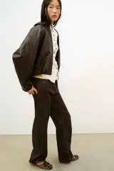 Sandalia plana estilo cangrejera con acabado efecto terciopelo en color marrón. Presenta diseño de tiras cruzadas, cierre mediante hebilla metálica lateral y punta redonda.