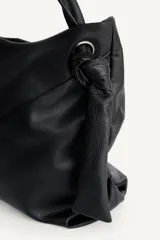 Bolso tipo shopper de hombro confeccionado en piel de alta calidad, con diseño minimalista y cierre principal mediante cremallera. Cuenta con un bolsillo interior con cierre y asa ajustable.