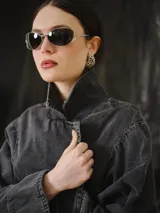 Trench largo de denim gris lavado, de silueta recta y amplia, con solapas amplias, mangas largas y botonadura frontal.