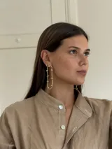 Caravanas de bronce con diseño ovalado alargado, decoradas con pequeñas esferas soldadas a lo largo de la estructura.