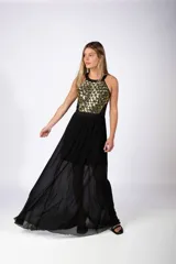 Vestido largo de fiesta con cuerpo superior decorado con apliques geométricos dorados y falda fluida de gasa negra con transparencia.