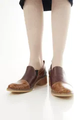 Zapatos de cuero negro con textura de cocodrilo en la puntera y el talón, de corte bajo, con elásticos laterales y taco cuadrado.