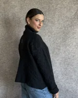 Sweater de lana color crudo con cuello alto y diseño trenzado.