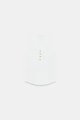 Top de algodón blanco con escote redondo, sin mangas y cierre frontal con pequeños botones. Presenta un diseño acanalado y bajo redondeado.