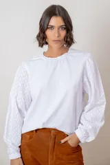 Remera de algodón color azul marino, con cuello redondo fruncido y mangas largas abullonadas con puños elásticos.