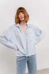 Camisa color crema de algodón con cuello camisero, botones y detalles de encaje en el escote.