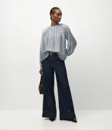 Blusa de viscosa con estampa geométrica en tonos celestes y grises, cuello redondo fruncido y mangas largas abullonadas.