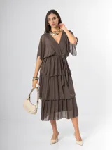 Vestido midi de seda italiana color marrón, con escote en V, mangas murciélago holgadas y falda en capas con volados. Cuenta con cintura elastizada y lazo ajustable al tono.