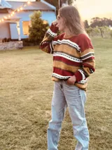 Sweater de lana con rayas horizontales en tonos rojo, ocre, marrón y blanco.