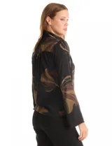 Camisa de crepe con estampado floral en tonos verdes y marrones, cuello con solapa, cierre frontal con botones y detalle de mostacillas bordadas en los hombros. Presenta mangas largas con terminación amplia.