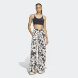 Pantalón Adidas de satén con estampado animal print tipo vaca en tonos blanco y negro, de corte holgado, perneras anchas y fluidas, cintura elástica y las icónicas 3 tiras de la marca en los laterales.