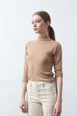 Polera de algodón color blanco, con cuello alto y mangas tres cuartos. Presenta un diseño ajustado al cuerpo con costuras decorativas en las sisas.