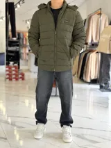 Campera puffer azul marino con capucha ajustable, cierre frontal y bolsillos laterales con cierre a presión. Cuenta con parche redondo con la inscripción "TURK" en el pecho.