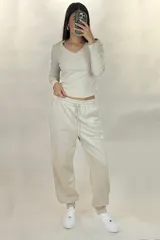 Pantalon deportivo tipo babucha de color beige, con cintura elástica ajustable mediante cordón y puños elásticos en los tobillos.