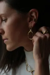 Aros colgantes de diseño artesanal con eslabones irregulares de textura orgánica y acabado en tono dorado.