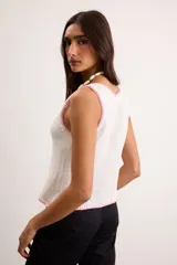 Musculosa de punto color blanco crudo, con escote en V y terminaciones con bordado artesanal amarillo.