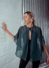 Capa de microtul color verde oscuro con diseño versátil, cierre frontal con botón y corte amplio con caída fluida.