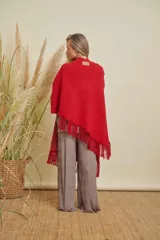 Ruana tejida color rojo, con terminación en flecos de lana y diseño en V en la espalda.