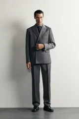 Blazer regular fit de Zara confeccionada en 100% lana, de color gris con diseño de rayas diplomáticas. Presenta cuello con solapas de pico, manga larga con botones en los puños, bolsillos con solapa en la cadera y bolsillo de vivo en el pecho. Cuenta con cierre frontal de botonadura cruzada.
