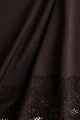 Pollera midi color marrón oscuro de punto, con cintura elástica y diseño asimétrico en el bajo adornado con detalle de encaje.