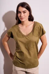 Remera de algodón color blanco con cuello en V y mangas cortas. Presenta un diseño con flores bordadas en relieve y detalles calados en el tejido.