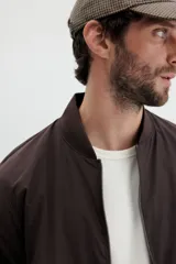 Campera bomber de color marrón oscuro, con cuello, puños y bajo acanalados. Posee cierre frontal y bolsillos laterales con cierre.