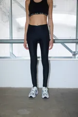 Calza negra de lycra gruesa con alforzas a la altura de la rodilla y tiro alto.