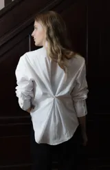 Camisa de algodón con corte clásico, cuello camisero y mangas largas con puños abotonados. Presenta un bordado geométrico en color bordó en la parte frontal y detalle de frunce en la espalda.