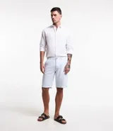 Bermuda de hombre en lino color gris claro, de corte recto, con textura discreta, bolsillos laterales y cierre frontal con botón y cremallera.