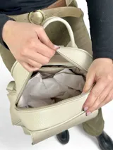 Mochila de cuero color crema con bolsillo frontal con textura de piel de cocodrilo.