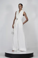 Mono largo de lino blanco, con escote en V, sin mangas, cinturón con hebilla forrada y pantalón palazzo.