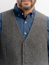 Chaleco de paño con escote en V, cierre frontal con botones y bolsillos tipo ojal. Presenta un diseño clásico de corte regular.