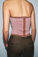 Corsé strapless con aros, confeccionado con una base de tela lisa color marrón y una capa superior de tul drapeado en color rosado.