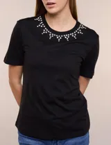 Remera blanca de calce recto y cuello redondo, confeccionada en suave jersey con detalle de aplicación de piedras brillantes a modo de gargantilla en el escote.