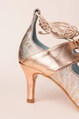 Zapato de tacón de 6 cm de alto color rosa nude, con cordones y borlas.