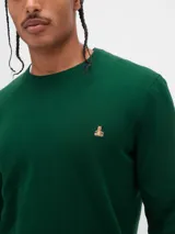 Buzo de tejido liso color verde oscuro, con cuello redondo y un pequeño logo bordado en el pecho.