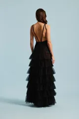 Vestido largo de fiesta color negro, con cuerpo bordado con apliques brillantes, escote en V profundo con inserción transparente, y falda escalonada de volados de tul.