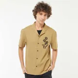 Camisa de manga corta color beige con cuello cubano y bordado de flores en el pecho.