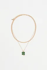 Collar doble de metal dorado, compuesto por una cadena tipo serpiente y una cadena fina con dije de trébol de cuatro hojas en acrílico verde.