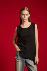 Musculosa de poliéster color nude, con cuello redondo y diseño asimétrico sin mangas.