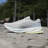 Championes de running Adidas Supernova Rise 2, color gris con detalles en celeste y amarillo. Incorporan mediasuela Dreamstrike+ y sistema Support Rods. Reconocidas por la American Podiatric Medical Association.