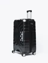 Valija rígida de viaje color negro con diseño geométrico en relieve, manija telescópica y cuatro ruedas con giro de 360°.