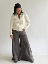 Sweater tipo campera de punto color crema, con diseño de trenzas verticales, cuello alto y cierre frontal completo.